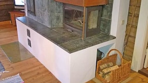 Eine moderne Küche mit integriertem Kamin, Fernseher und Holzkorb.
