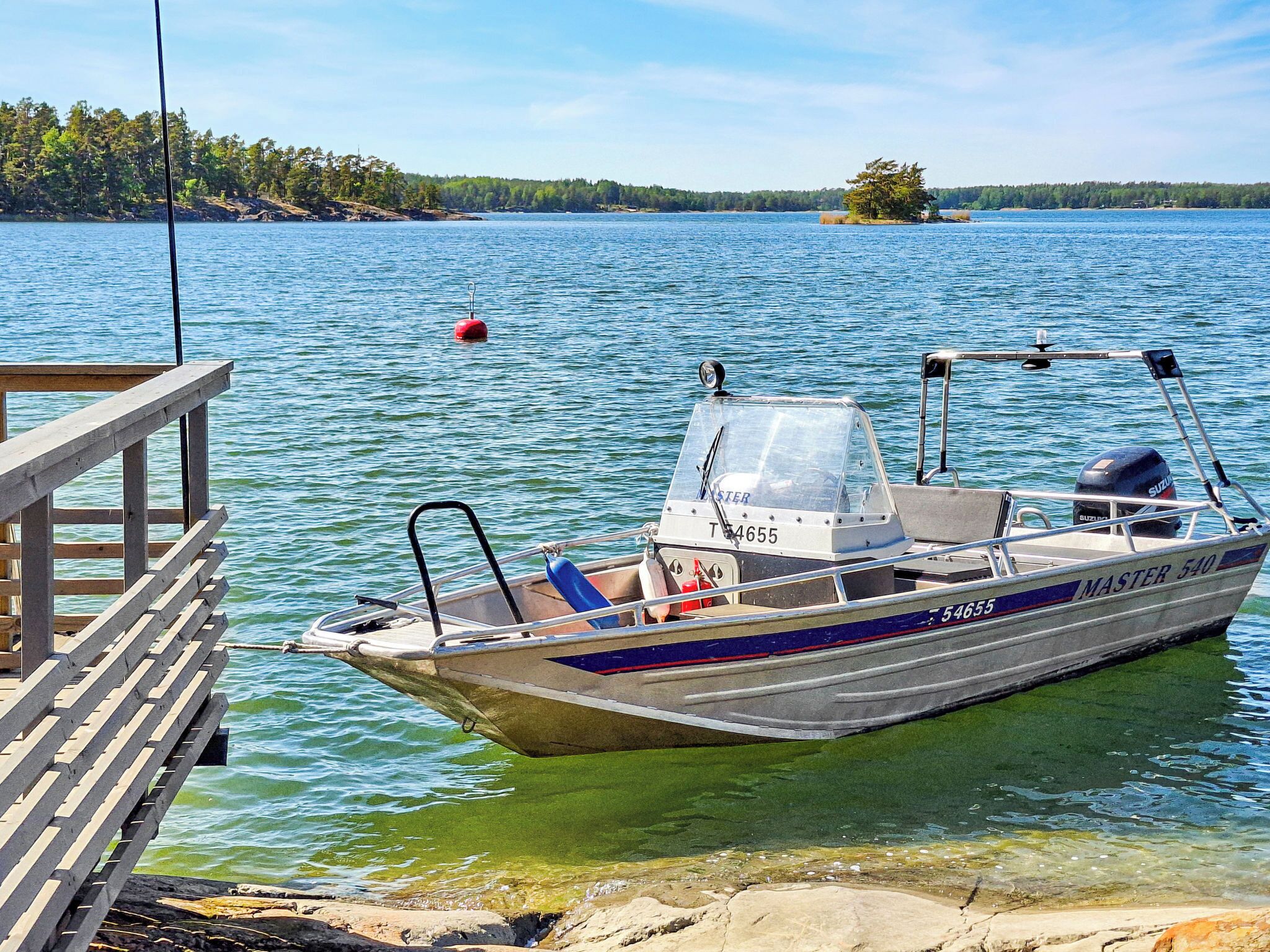 A boat docked at a pier with a clear view of a lake and distant shoreline.