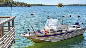 A boat docked at a pier with a clear view of a lake and distant shoreline.