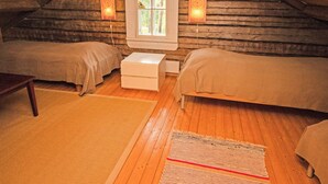 Une chambre mansardée accueillante, avec deux lits, une fenêtre et une petite table.