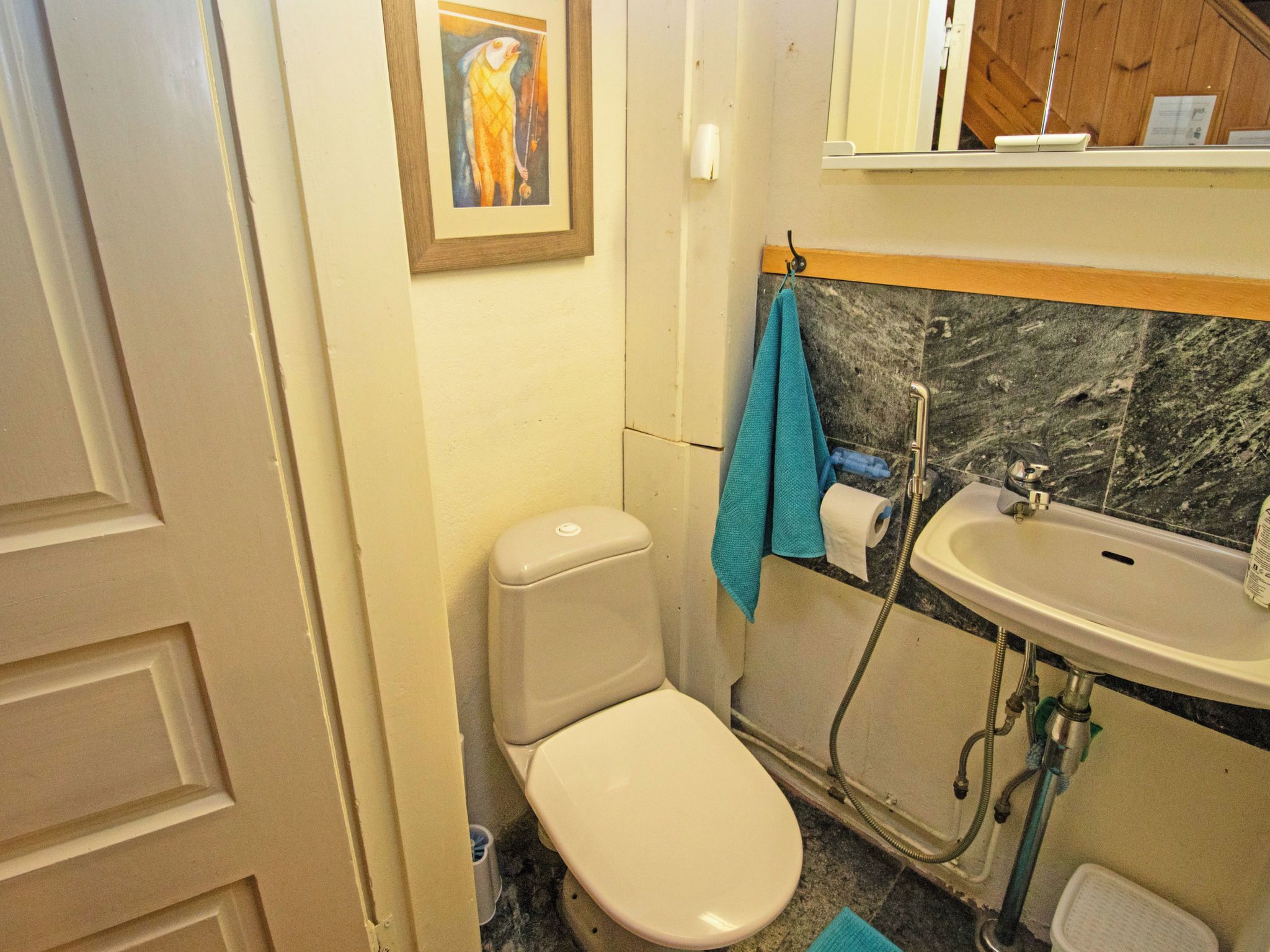 A small bathroom with a toilet, sink, and a towel hanging on the wall.