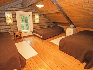 Une chambre confortable située sous les toits, avec un plancher en bois, un lit, une table de chevet et une fenêtre.