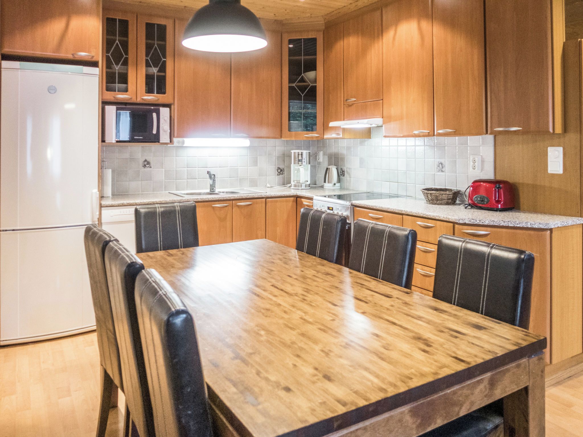 A kitchen with wooden cabinets, a stainless steel refrigerator, a microwave, a coffee maker, and a toaster.