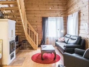 Ein Holzinnenraum mit einer Treppe, einem Sofa, einem Couchtisch und einem Kamin.