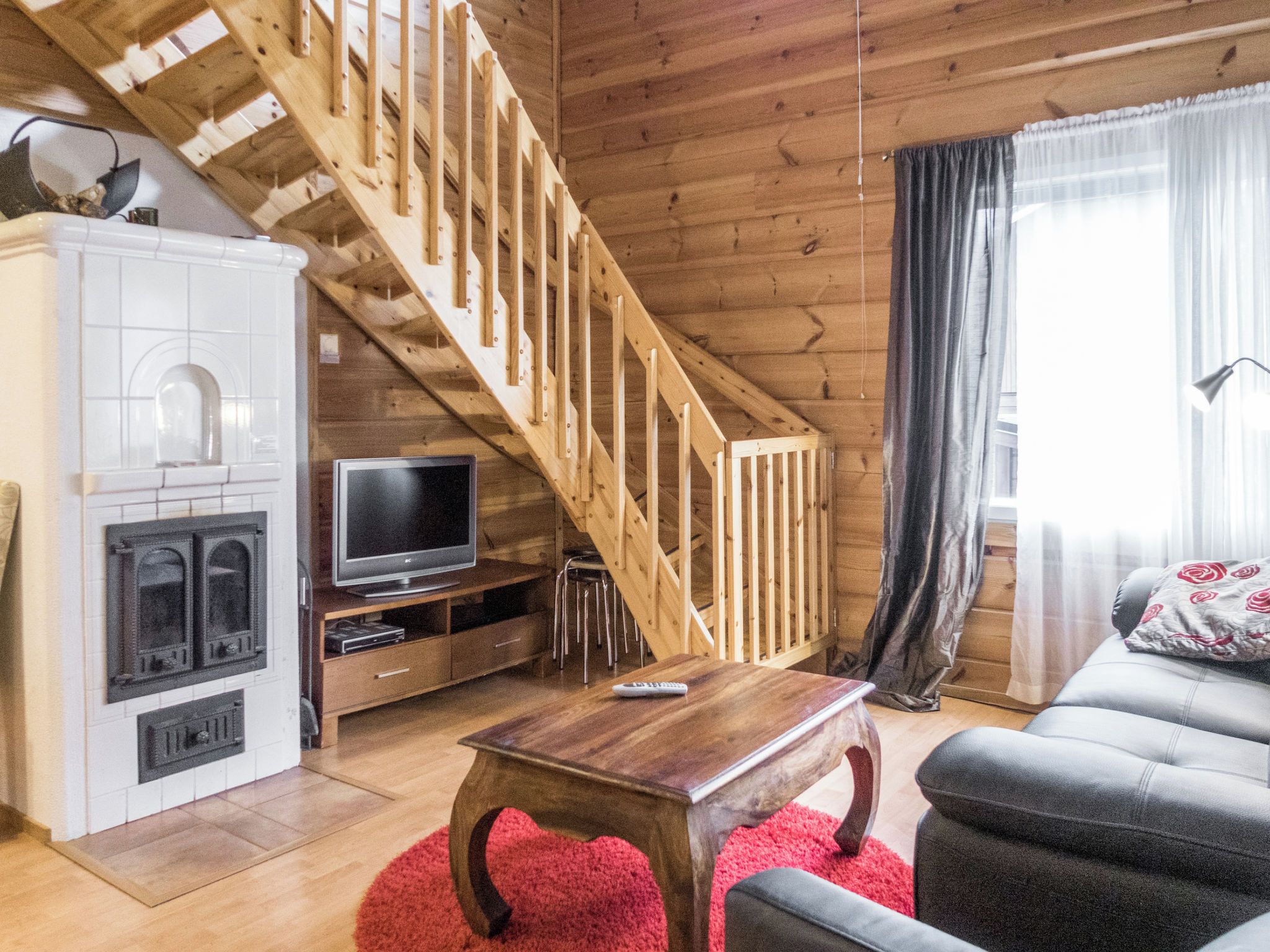 Un salon chaleureux avec un escalier en bois, une cheminée, un téléviseur et un coin salon confortable.