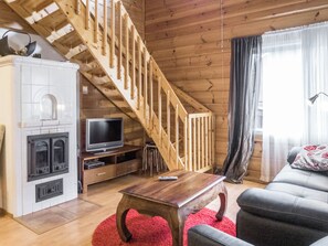 A cozy living room with a wooden staircase, a fireplace, a television, and a comfortable seating area. - Klz 10. opaali by Interhome (Sotkamo)