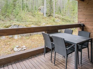 Eine Holzterrasse mit Tisch und Stühlen, mit Blick auf ein bewaldetes Gebiet.