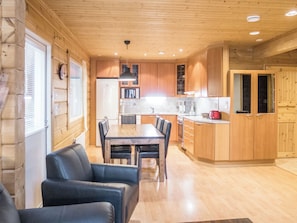 A wooden interior with a dining table, chairs, and a kitchen area. - Klz 10. opaali by Interhome (Sotkamo)