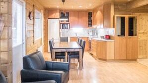 Una cocina moderna con armarios de madera, una zona de comedor con mesa y sillas, y un refrigerador.