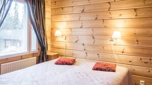 Una habitación con paneles de madera, una cama, dos lámparas de noche y un ventanal con cortinas.