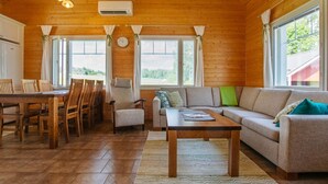 A cozy cabin interior with a wooden dining table, chairs, a sofa, and a coffee table. - Talvikki by Interhome (Kuopio)
