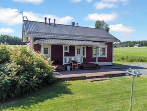 A red brick house with a tiled roof, a porch with a table and chairs, and a grassy yard. - Talvikki by Interhome (Kuopio)