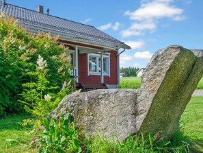 A red house with a white window and a large rock in the foreground. - Talvikki by Interhome (Kuopio)