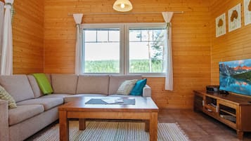 A cozy living room with a sofa, a coffee table, and a television on a wooden stand.