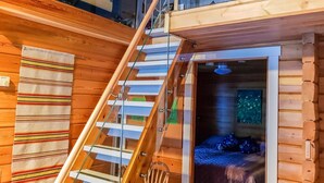 A wooden cabin with a glass staircase leading to a loft area.