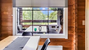 A wooden cabin interior with a large window overlooking a deck.