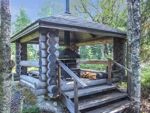 A log cabin with a chimney, a fireplace, and a set of stairs leading up to a porch area.