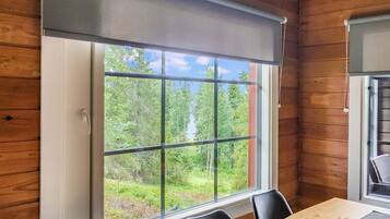A room with a large window, wooden walls, a table, and chairs.