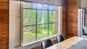 A room with a large window offering a view of a forest.