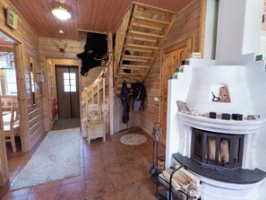 A log cabin interior with a fireplace, wooden staircase, and a coat rack.