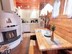A cozy kitchen with wooden cabinets, a dining table with a vase, and a fireplace.