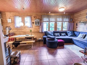 A cozy cabin interior with a wooden interior, a sofa, a table, and a fireplace.