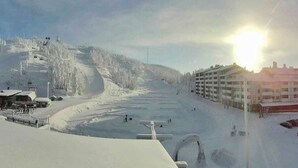 A snow-covered ski slope with a building complex on the right.