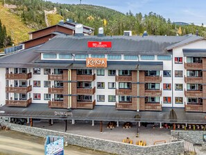 Un hotel de varios pisos con balcones, un letrero que indica 'chalés de esquí' y un restaurante llamado 'Kuks'.