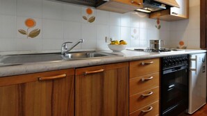 Una cocina con armarios de madera, un fregadero de acero inoxidable, un lavavajillas y una estufa.