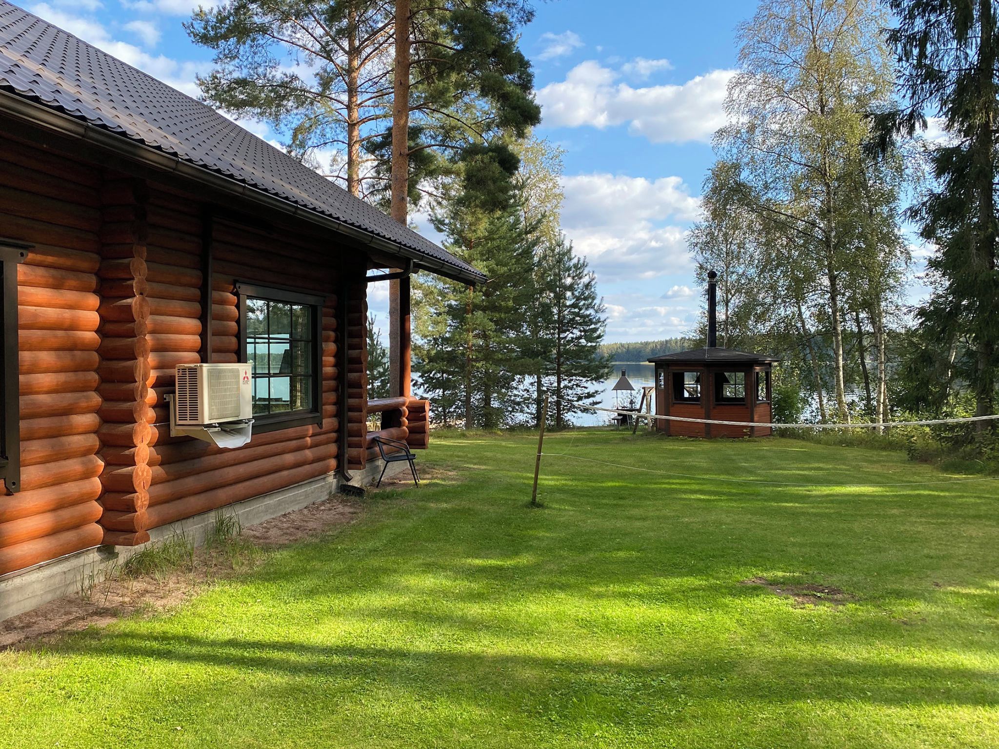 A log cabin with a covered porch and a view of a lake.