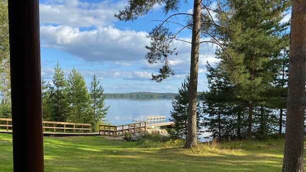 Vista su un lago con un molo di legno e tavoli da picnic.