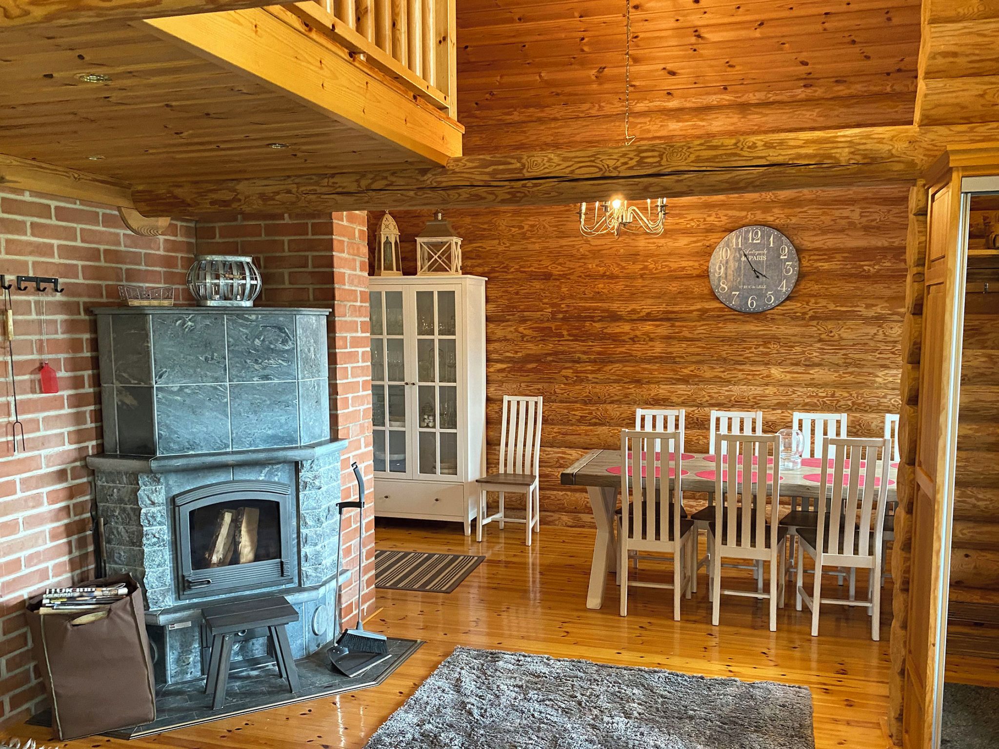 A cozy cabin interior with a stone fireplace, wooden dining table, and chairs.
