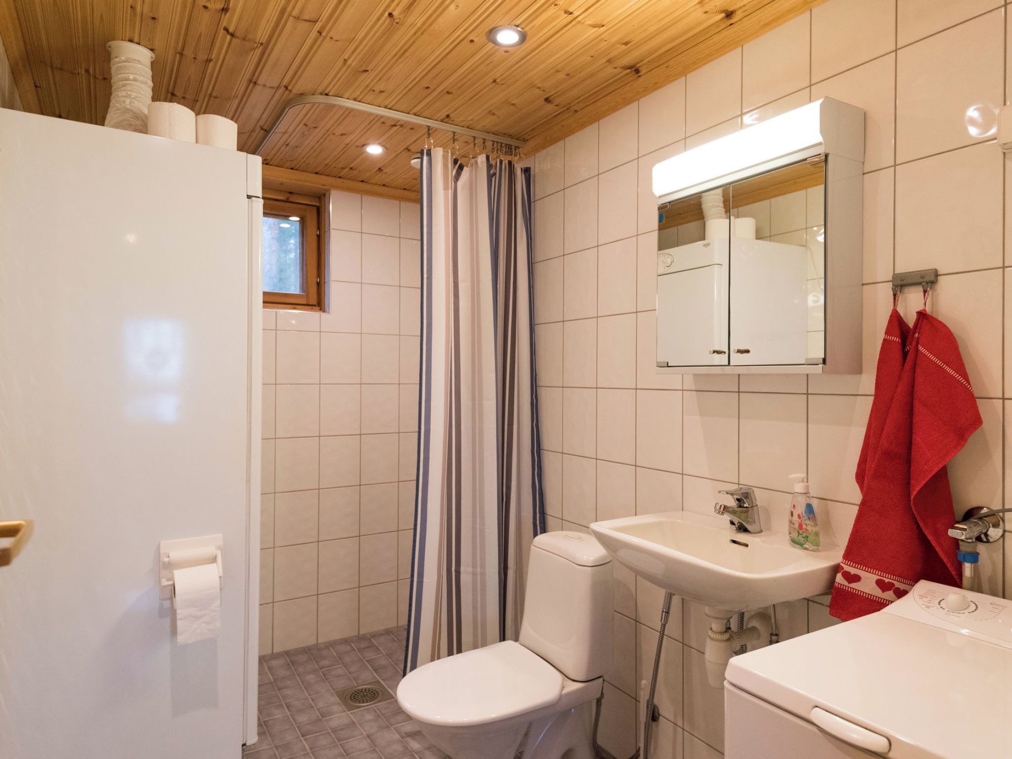 Et badeværelse med bruser, toilet, håndvask og spejl.