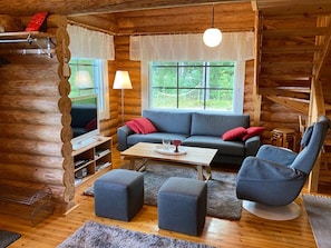 A cozy cabin interior with a sofa, armchair, ottoman, and a small table with a tray. - Raatiannokka by Interhome (Ikaalinen)