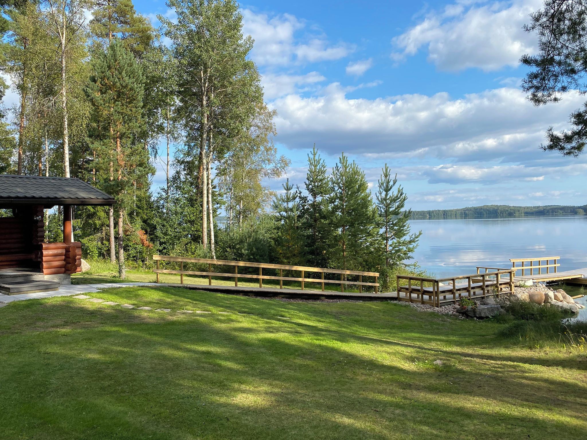 Un chalet au bord du lac, doté d’une terrasse en bois et d’un quai s’avançant dans l’eau.