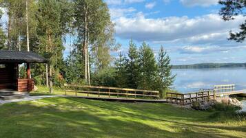 Un chalet au bord du lac, doté d’une terrasse en bois et d’un quai s’avançant dans l’eau.