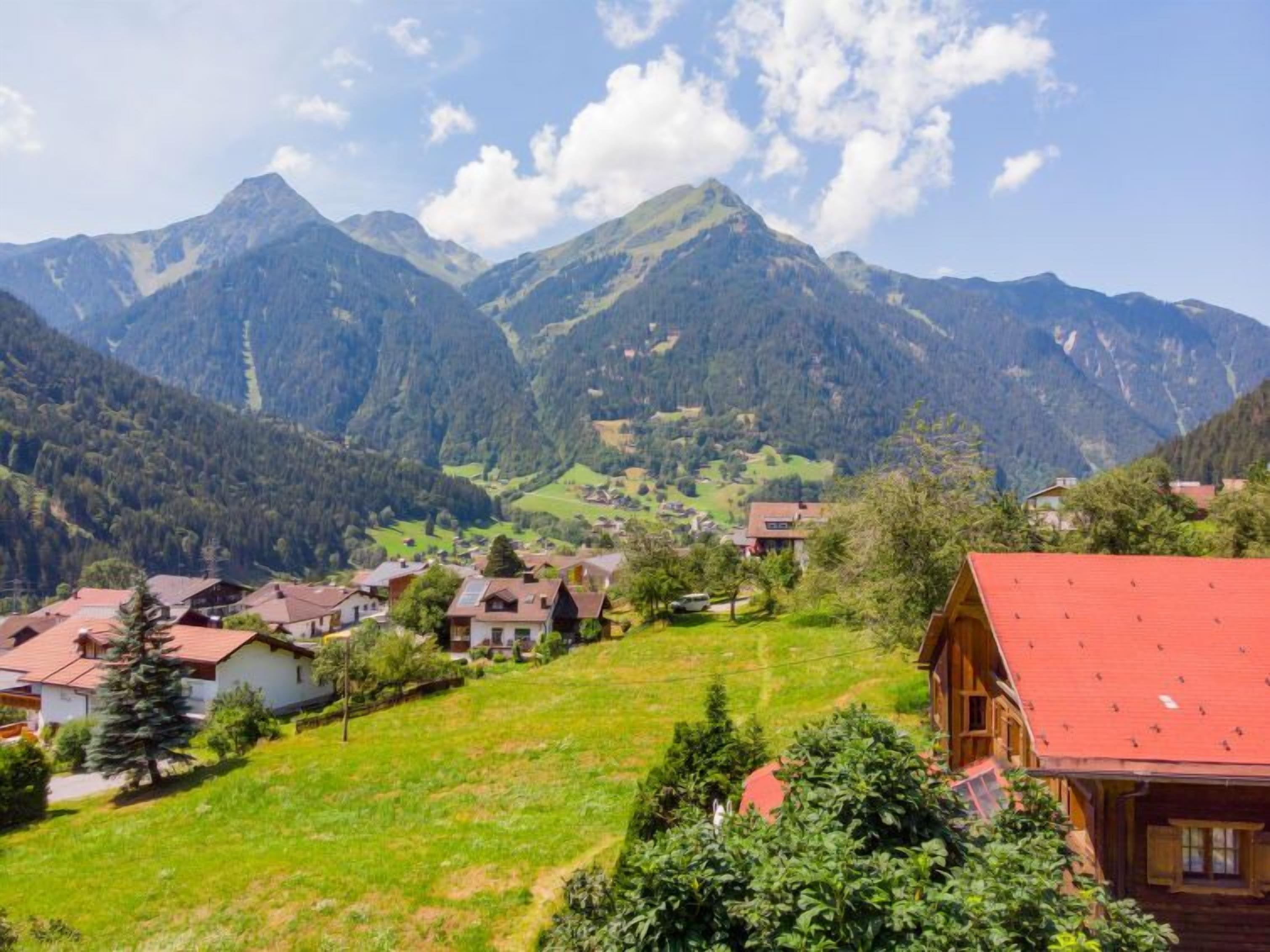 A mountainous village with traditional houses, a clear sky, and lush greenery.