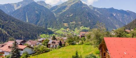 A mountainous village with traditional houses, a clear sky, and lush greenery.