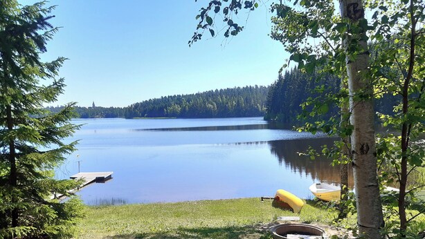A lakeside view with a dock, a yellow boat, and a fire pit area. - Piilutupa by Interhome (Luhanka)