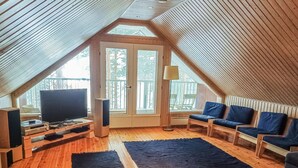 An attic room with a wooden floor, a TV, a speaker, and a sofa. - Piilutupa by Interhome (Luhanka)