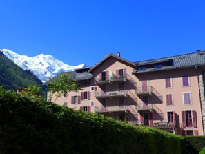 A multi-story building with balconies, set against a backdrop of snow-capped mountains. - L'Univers by Interhome (Chamonix)