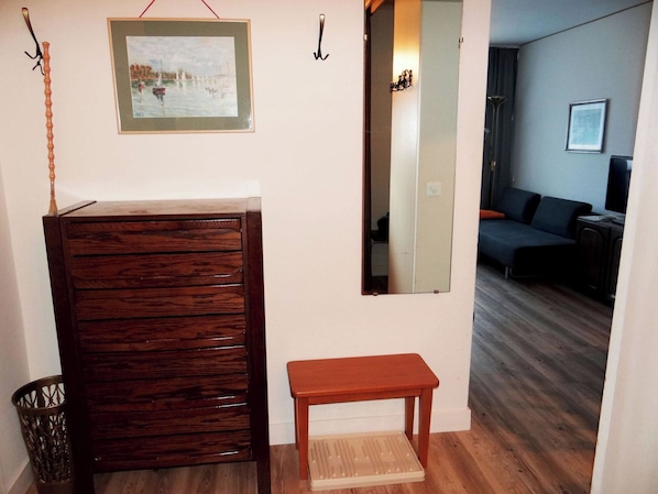 Une pièce comprenant un meuble en bois, un petit banc, un miroir et un tableau encadré accroché au mur.