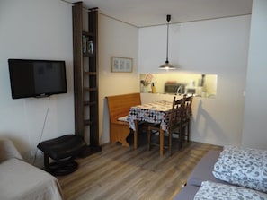 Une pièce de taille modeste comprenant un lit, un bureau avec une chaise, un téléviseur et une bibliothèque.
