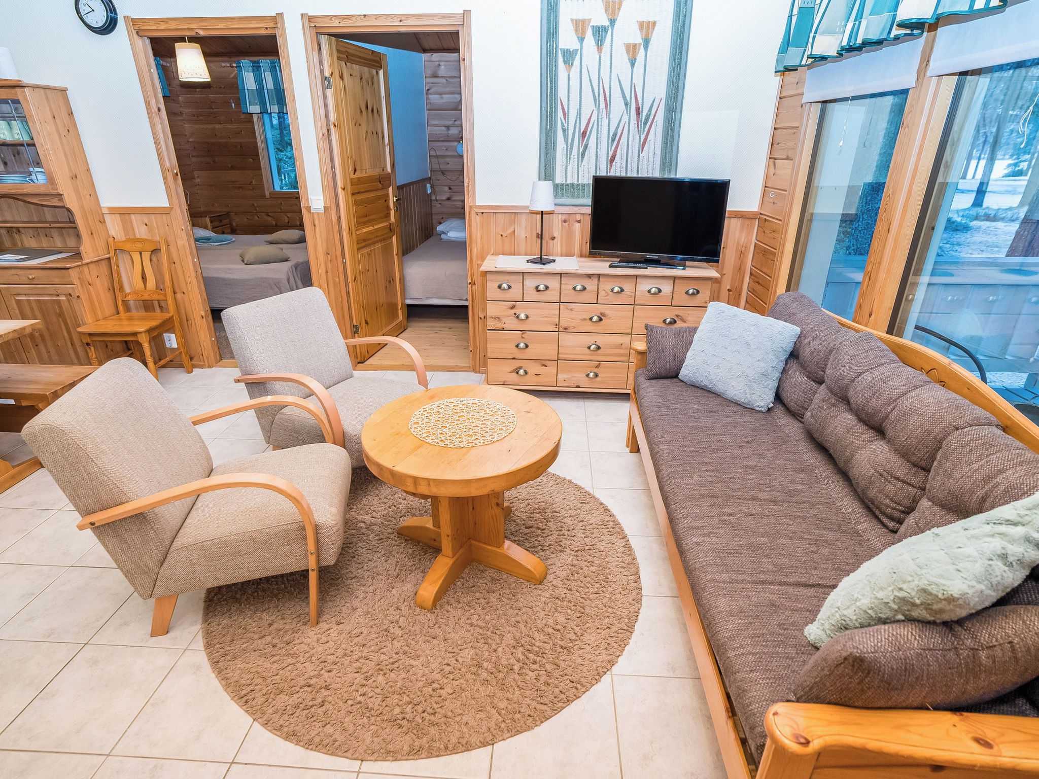 Un salon confortable avec un canapé, des fauteuils, une table basse et un téléviseur.