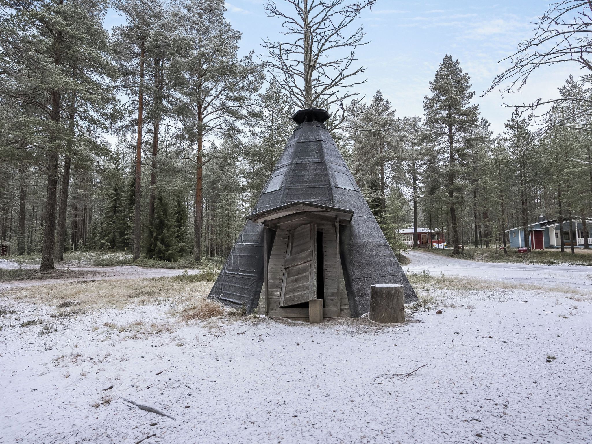 Une forêt enneigée, avec une structure conique qui ressemble à une habitation traditionnelle.
