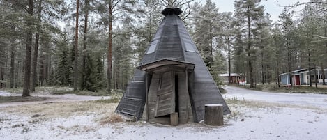 Een besneeuwd bos met een kegelvormige structuur die lijkt op een traditionele woning.