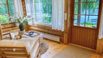 A wooden cabin with a bed, a table with a tray, and a window with curtains.