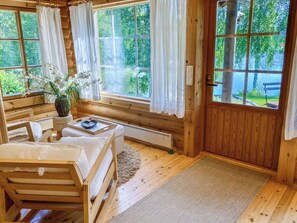 Een houten hutje met een bed, een tafel met een dienblad en een raam met gordijnen.