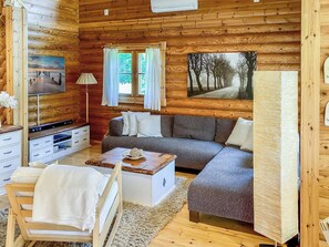 A cozy cabin interior with a sofa, a small table, a TV, and a painting on the wall. - Hartolan ilo by Interhome (Hartola)