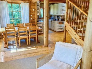 Un interior de madera con comedor, cocina y escalera.
